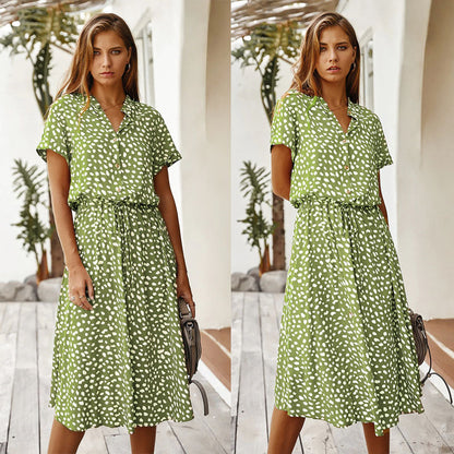 Frau in grünem Sommerkleid mit weißen Punkten, knielang, kurzärmelig, draußen stehend.