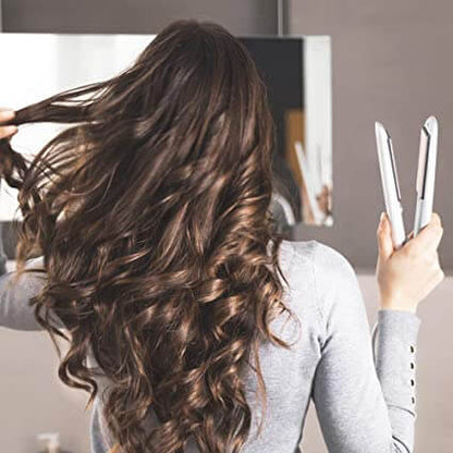 Frau mit Locken, hält weißen Haarglätter, Haarstyling, glattes Haar, Friseurwerkzeug.