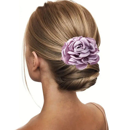 Frau mit Hochsteckfrisur und lila Rosen-Haarspange, elegantes Haaraccessoire.