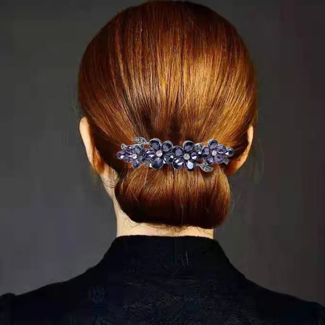 Frau mit braunem Haar, eleganter Haarklammer mit lila Blumen, Hochsteckfrisur, Rückansicht.