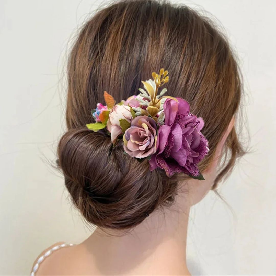 Frau mit Dutt und lila Blumen-Haarschmuck, elegantes Haaraccessoire, Hochzeit, Frisur.