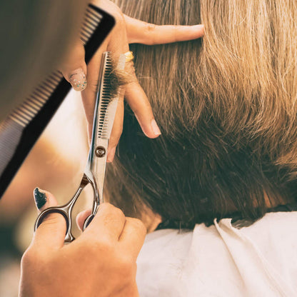 Friseurschere schneidet braunes Haar, Nahaufnahme, professionelles Friseurwerkzeug.