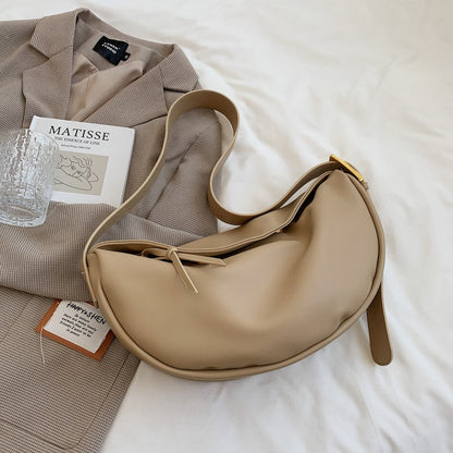 Beige Halbmond-Tasche aus Leder auf beigem Blazer, modisches Accessoire für Damen.