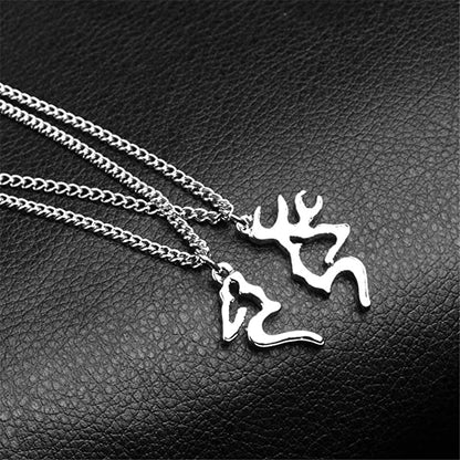 Silberne Hirsch- und Hirschkuh-Anhänger auf Kette, Schmuck auf schwarzem Lederhintergrund.