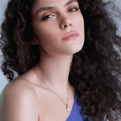 Frau mit lockigem Haar trägt blaues Oberteil und Perlenkette, Nahaufnahme, Modefotografie.