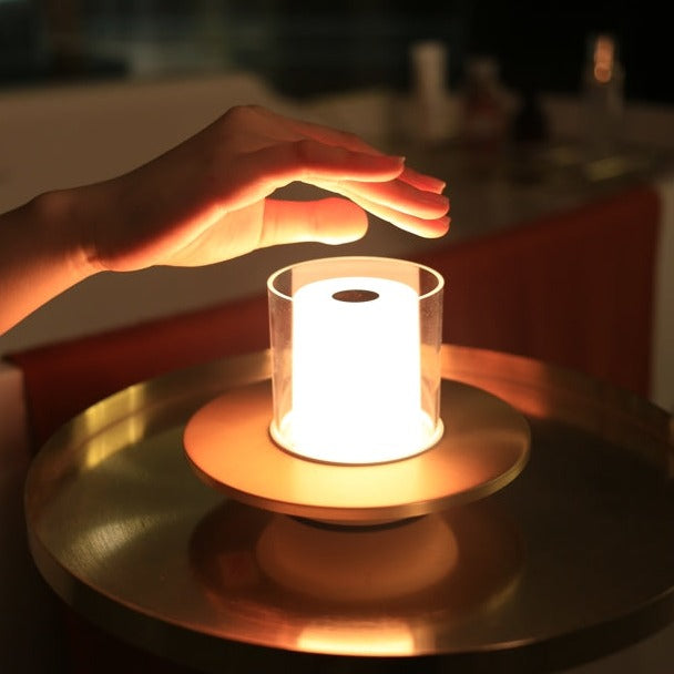 Hand über leuchtender LED-Tischlampe, modernes Design, warmes Licht, Glaszylinder, Nachtlicht.
