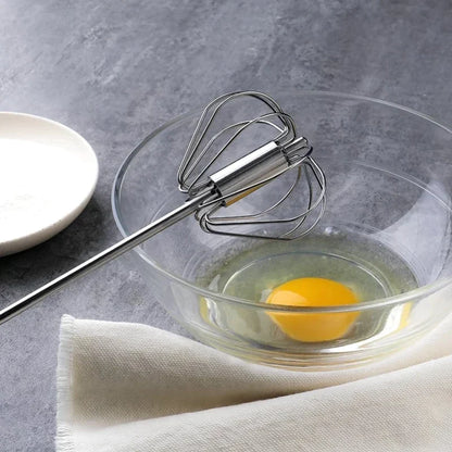 Handmixer aus Edelstahl, halbautomatisch, in Glasschüssel mit Ei, Küchenzubehör.