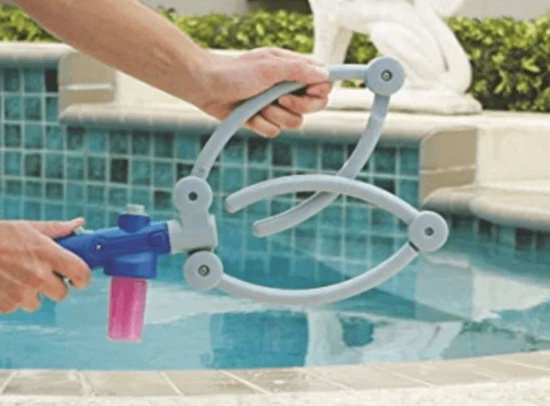 Graues Haustier-Duschwerkzeug mit blauem Griff und rosa Seifenbehälter am Pool.
