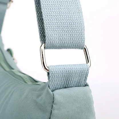Hellblaue Umhängetasche aus Stoff mit verstellbarem Riemen und silberner Metallschnalle.