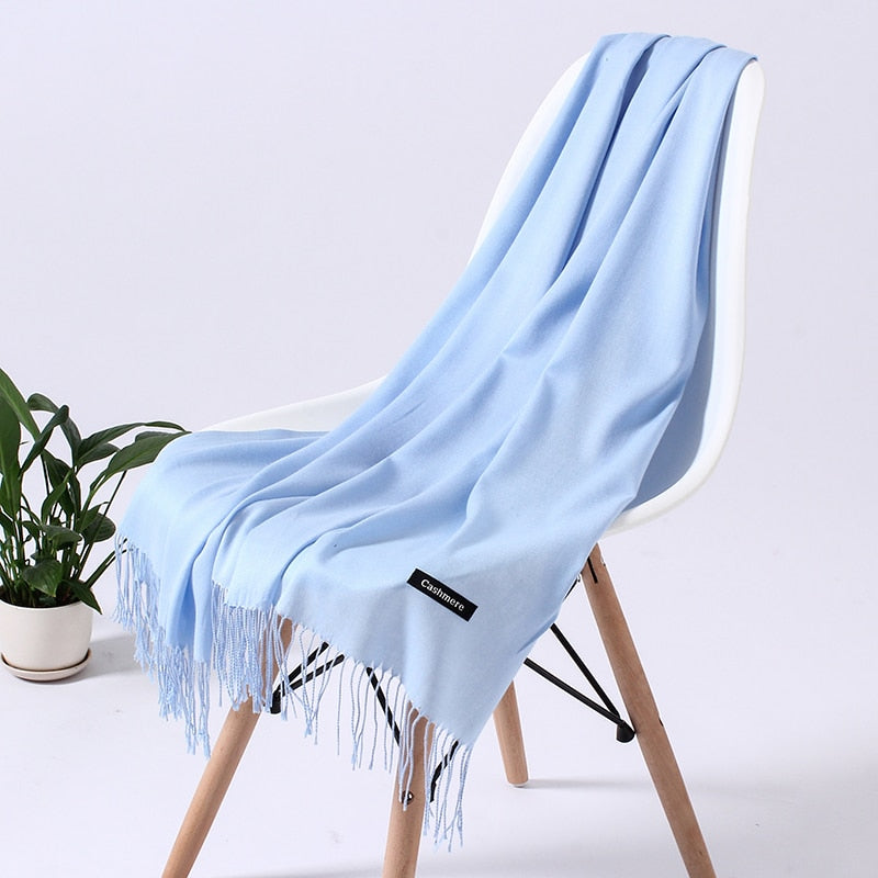 Hellblauer Kaschmirschal auf weißem Stuhl, weiches Material, modisches Accessoire, Wohnzimmer.
