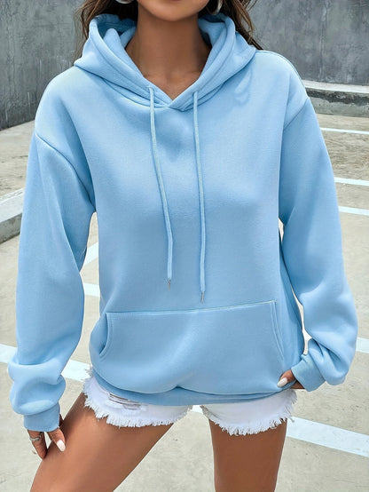 Frau in hellblauem Hoodie und weißen Shorts, lässige Mode, Streetwear, urbaner Stil.