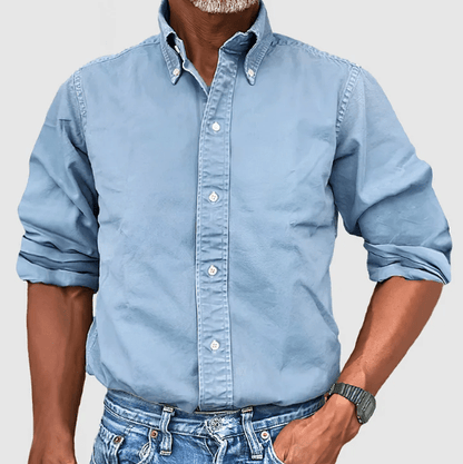 Mann in hellblauem Button-Down-Hemd aus Baumwolle, lässig gekrempelt, mit Jeans.