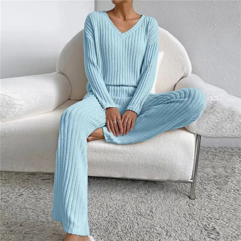 Frau in hellblauem Strick-Loungewear-Set auf weißem Sofa, gemütliche Damenmode.