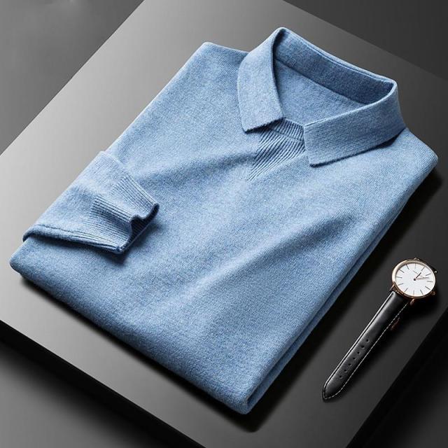 Hellblauer Herrenpullover aus Kaschmir, gefaltet, neben einer eleganten Armbanduhr auf schwarzem Tisch.