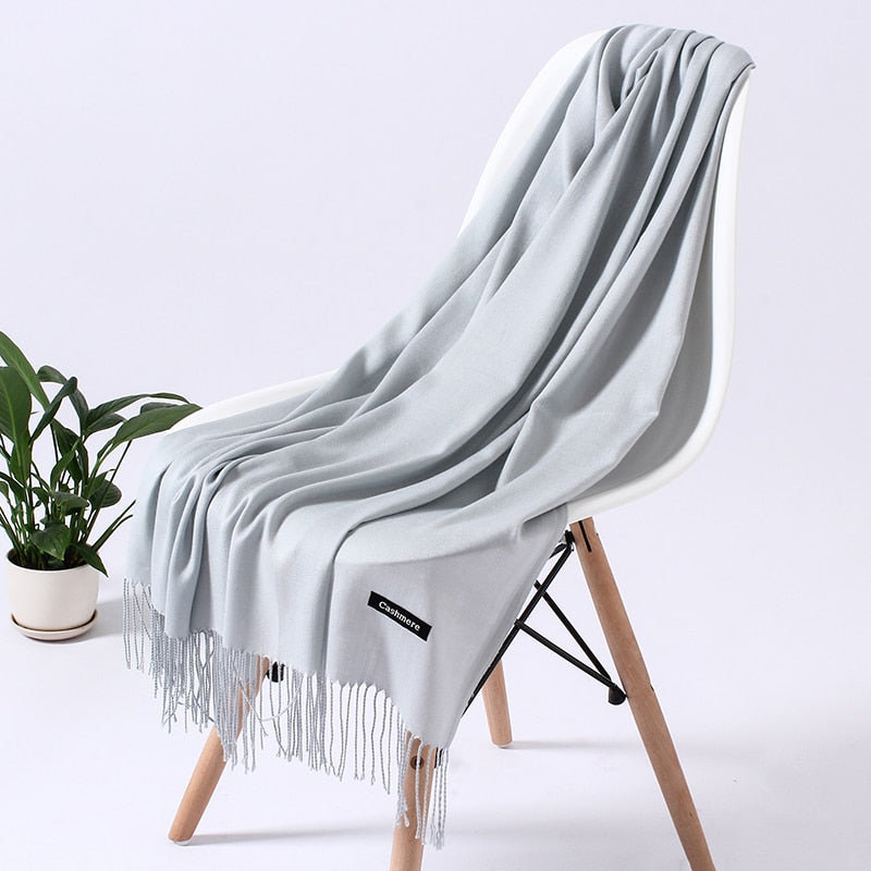 Grauer Kaschmirschal auf Stuhl, weiches Material, modisches Accessoire, Wohnzimmer-Dekoration.