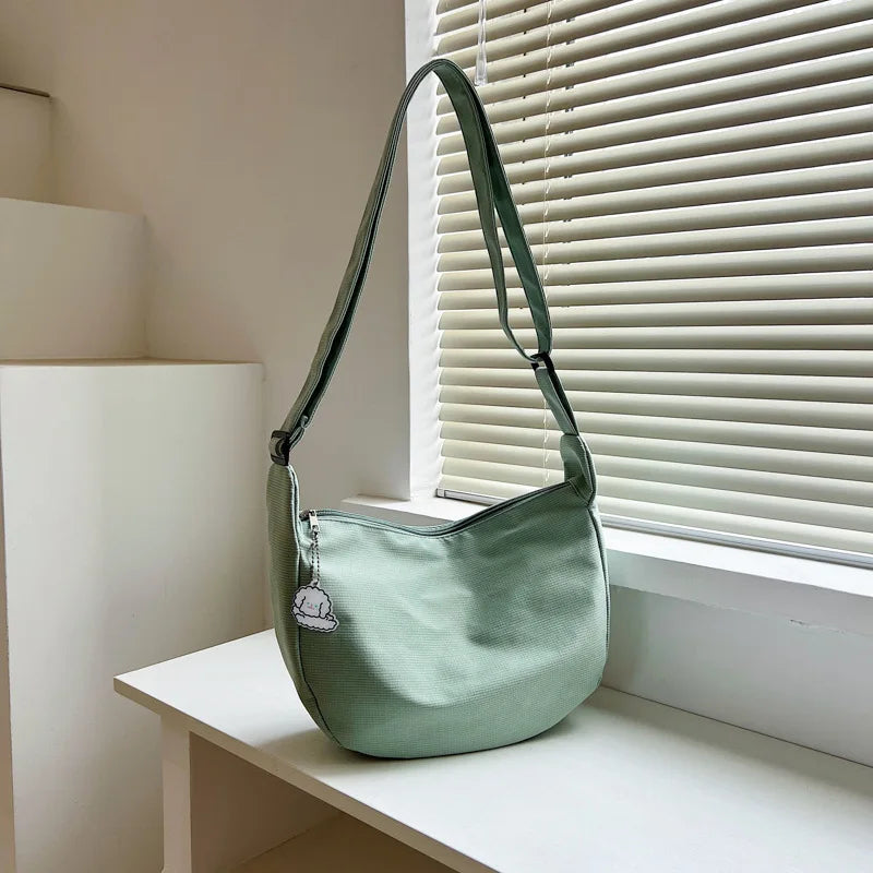 Hellgrüne Umhängetasche aus Stoff auf weißem Tisch, minimalistisches Design, Damenmode.