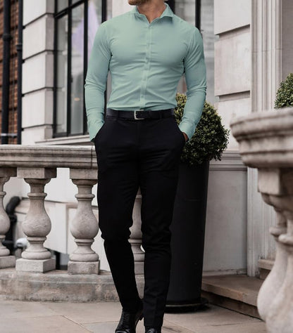 Mann in mintgrünem Hemd und schwarzer Hose, Business-Look, elegante Herrenmode, draußen.