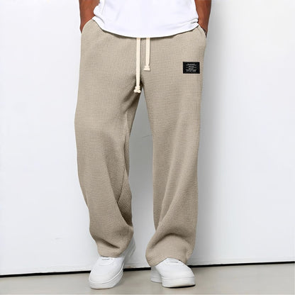 Modell i beige vaffelstickade byxor med vit dragsko, vit t-shirt och vita sneakers, framifrån 7