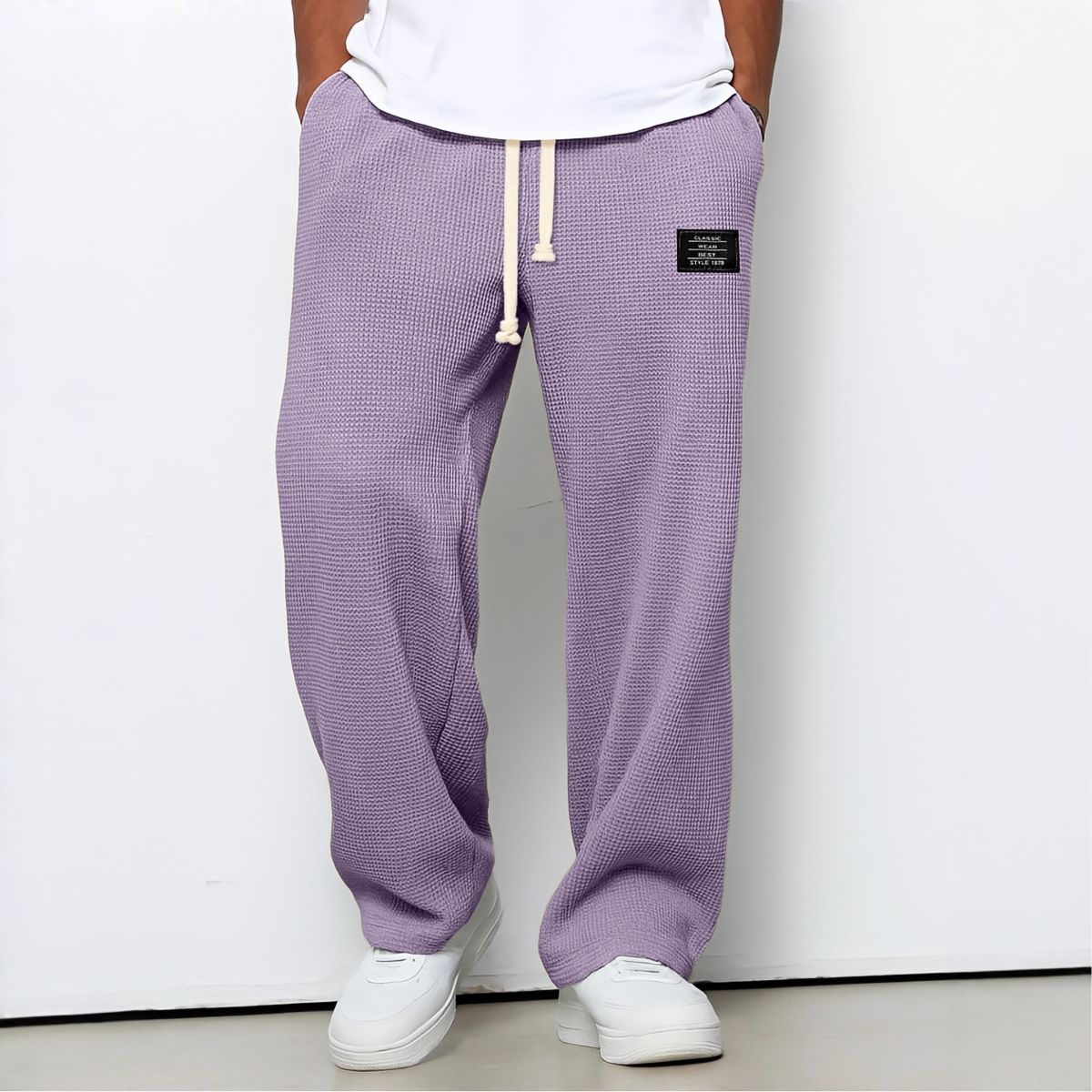 Modell i lila vaffelstickade byxor med vit dragsko, vit t-shirt och vita sneakers, framifrån 10