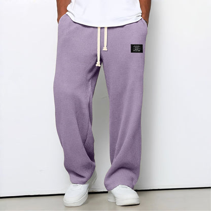 Modell i lila vaffelstickade byxor med vit dragsko, vit t-shirt och vita sneakers, framifrån 10
