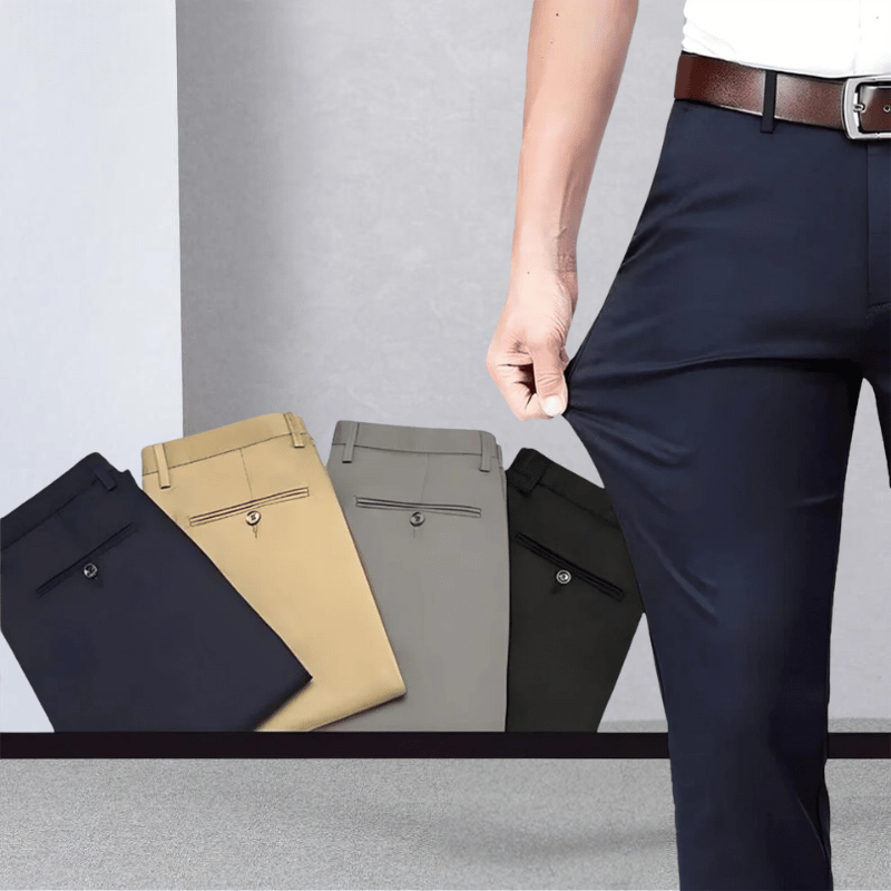 Mann in dunkelblauer Stretchhose, zeigt Flexibilität; beige, graue, schwarze Hosen im Hintergrund.