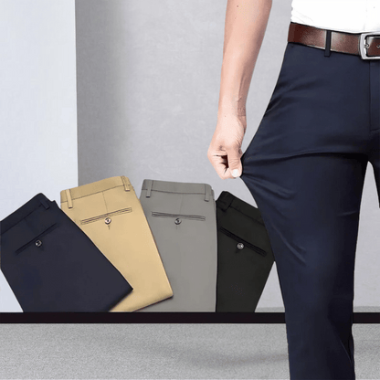 Mann in dunkelblauer Stretchhose, zeigt Flexibilität; beige, graue, schwarze Hosen im Hintergrund.
