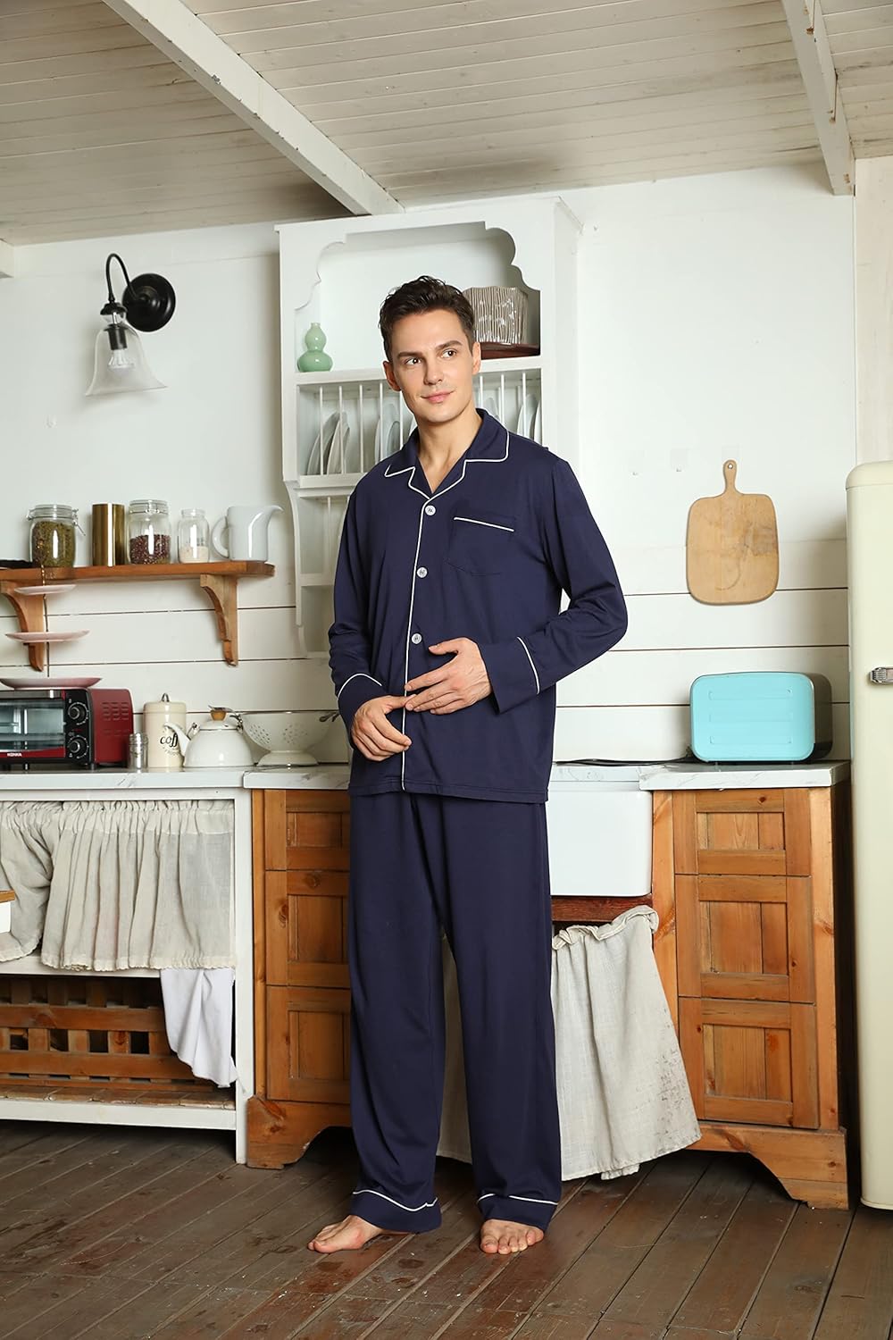 Mann in dunkelblauem Pyjama in rustikaler Küche, Holzregale, Retro-Kühlschrank.