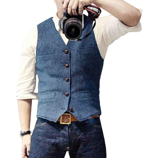 Mann in blauer Weste und Jeans, hält Kamera, modische Herrenbekleidung, Freizeitlook.