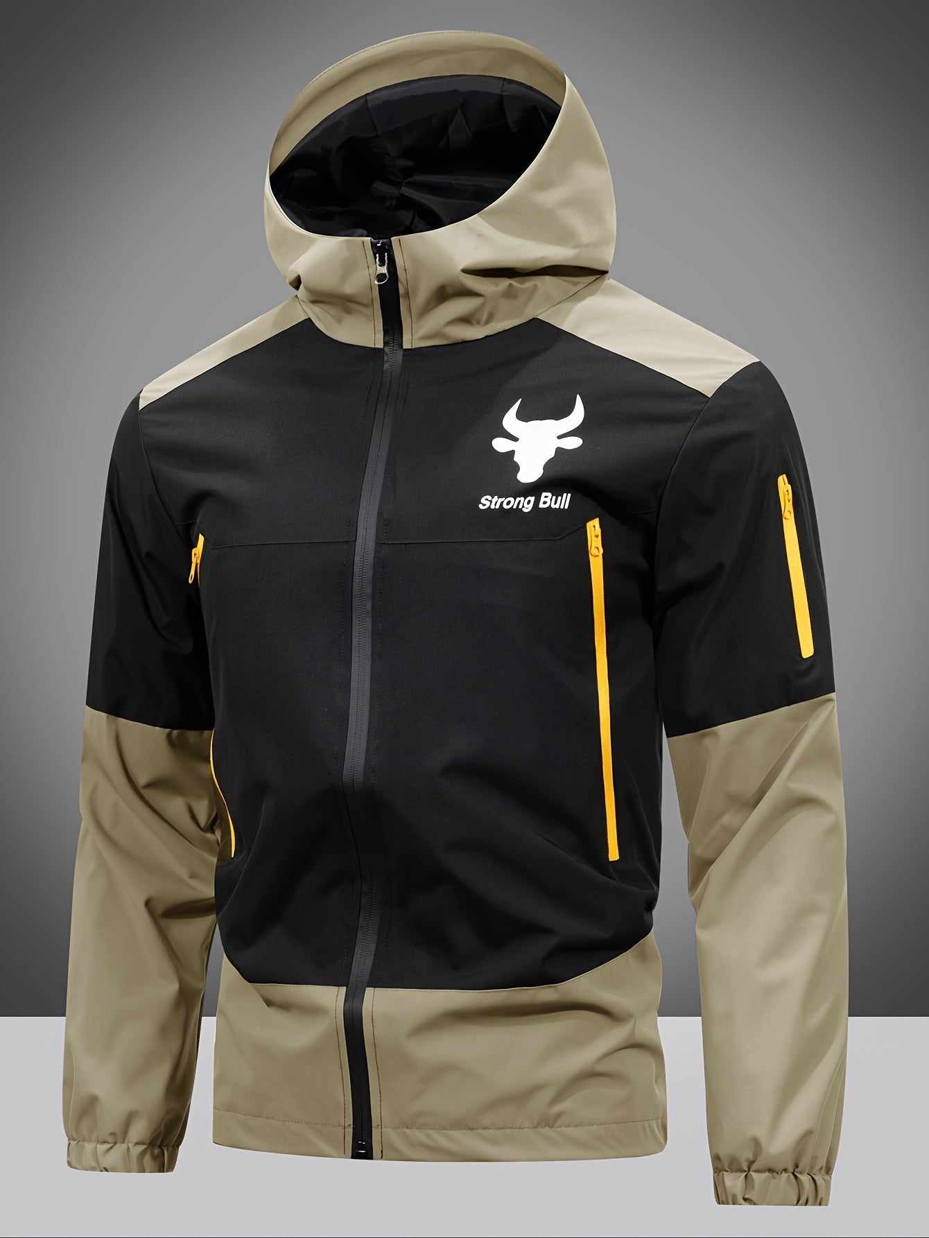 Schwarze und beige Outdoor-Jacke mit Kapuze, gelben Reißverschlüssen, "strong Bull" Logo.