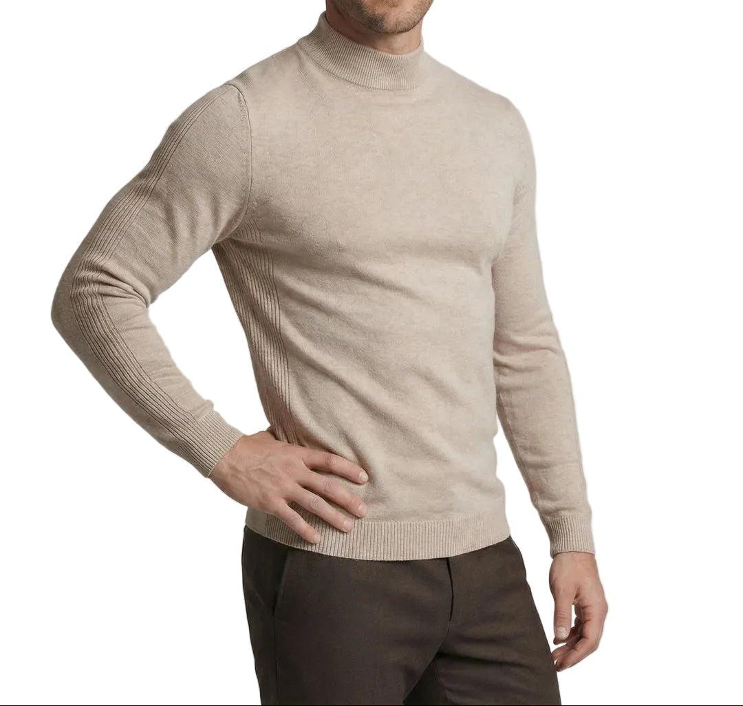 Man i beige tröja med ståkrage och ribbad kant, ena handen på höften, brun byxa 1