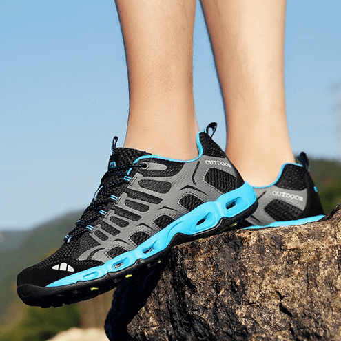 Schwarze und blaue Outdoor-Sportschuhe auf Felsen, atmungsaktiv, rutschfest, Herren.