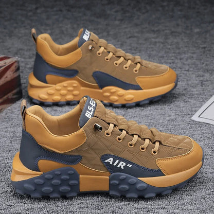 Braune und graue Herren-Sportschuhe, atmungsaktiv, mit Luftkissen-Sohle auf grauem Teppich.