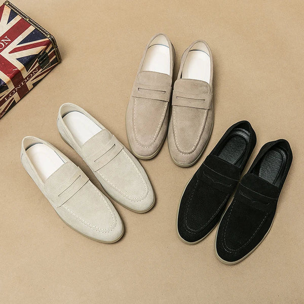 Drei Paar Herren-Slipper aus Wildleder in Beige, Sand und Schwarz auf braunem Hintergrund.