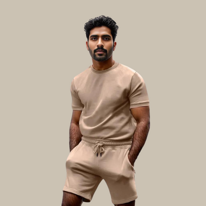 Mann in beigem T-Shirt und Shorts, Freizeitkleidung, Sommermode, neutraler Hintergrund.