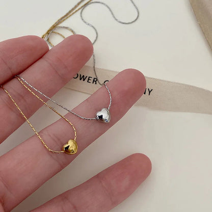 Goldene und silberne Herz-Halsketten auf Hand, Schmuck, minimalistisch, Geschenkideen.