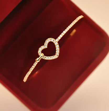 Goldenes Armband mit Herzanhänger und Diamanten in roter Schmuckschatulle, elegantes Design.