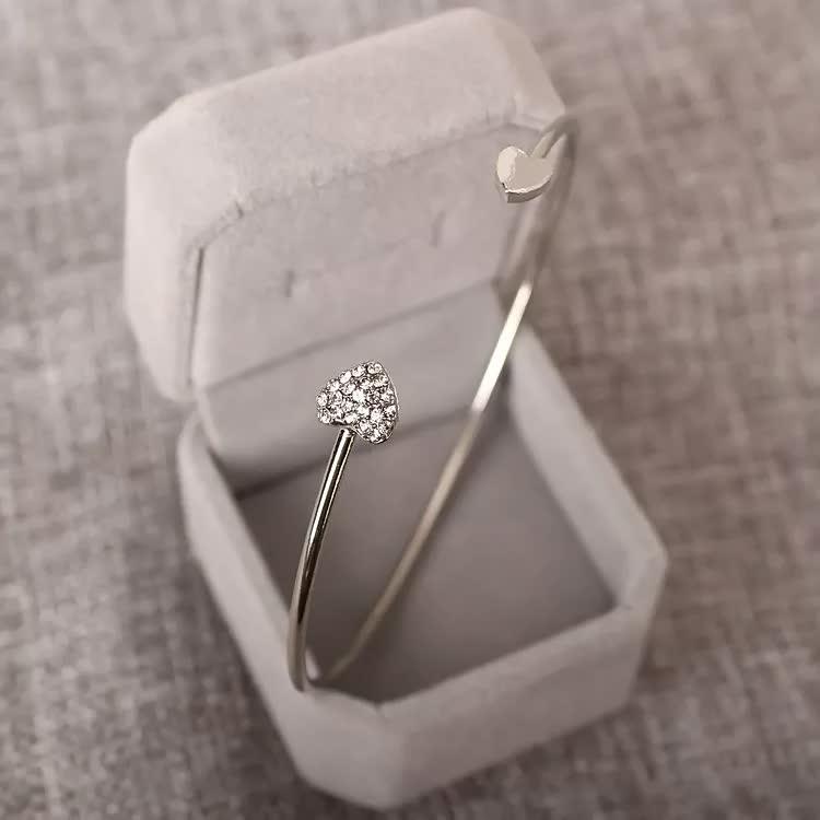 Silbernes Herzarmband mit Diamanten in grauer Schmuckschatulle, elegantes Schmuckdesign.