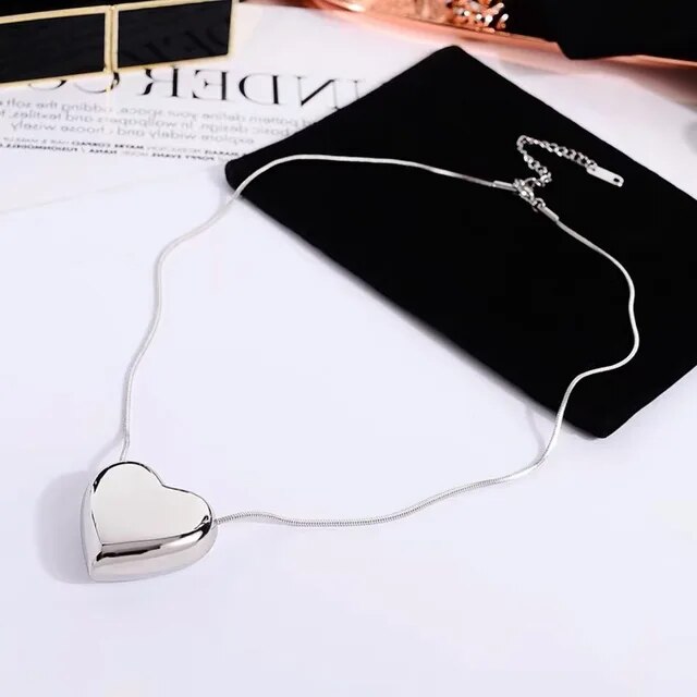 Silberne Herz-Halskette auf schwarzem Samtbeutel, elegantes Schmuckdesign, Geschenkidee.