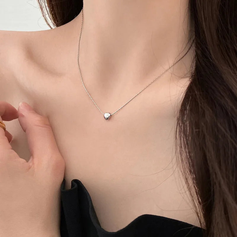 Silberne Herz-Halskette an Frau, eleganter Schmuck, minimalistisches Design, modisch.