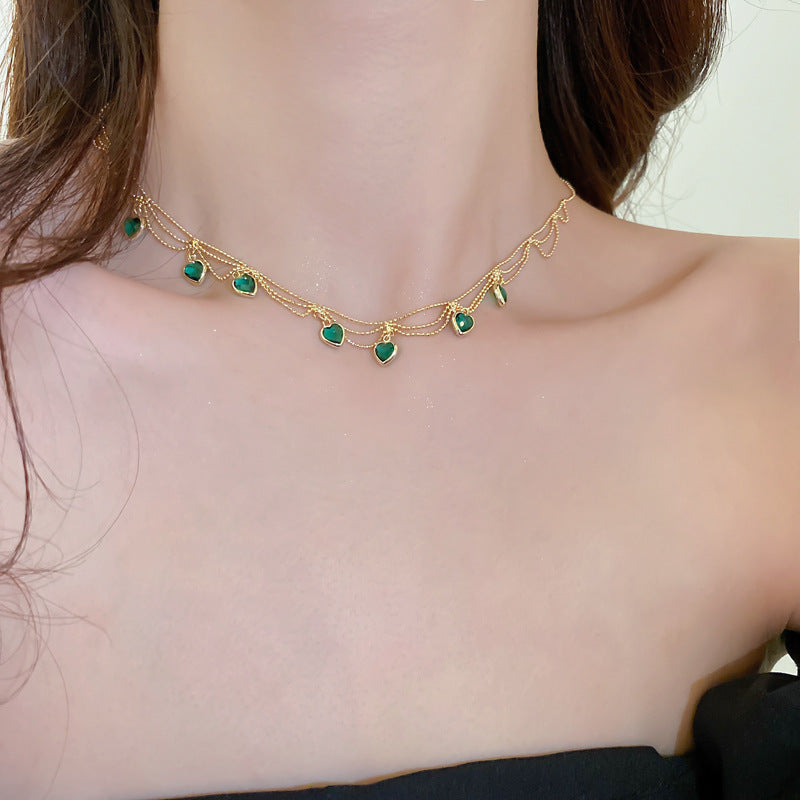 Goldene Halskette mit grünen Herzanhängern, eleganter Schmuck für Damen, modisches Accessoire.