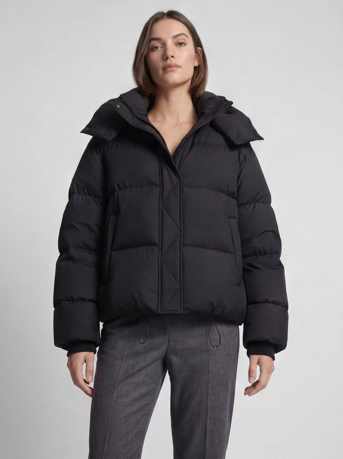 Närbild framifrån på kvinna i svart oversized jacka med blixtlås, täckt framkant och byxor i grått 6