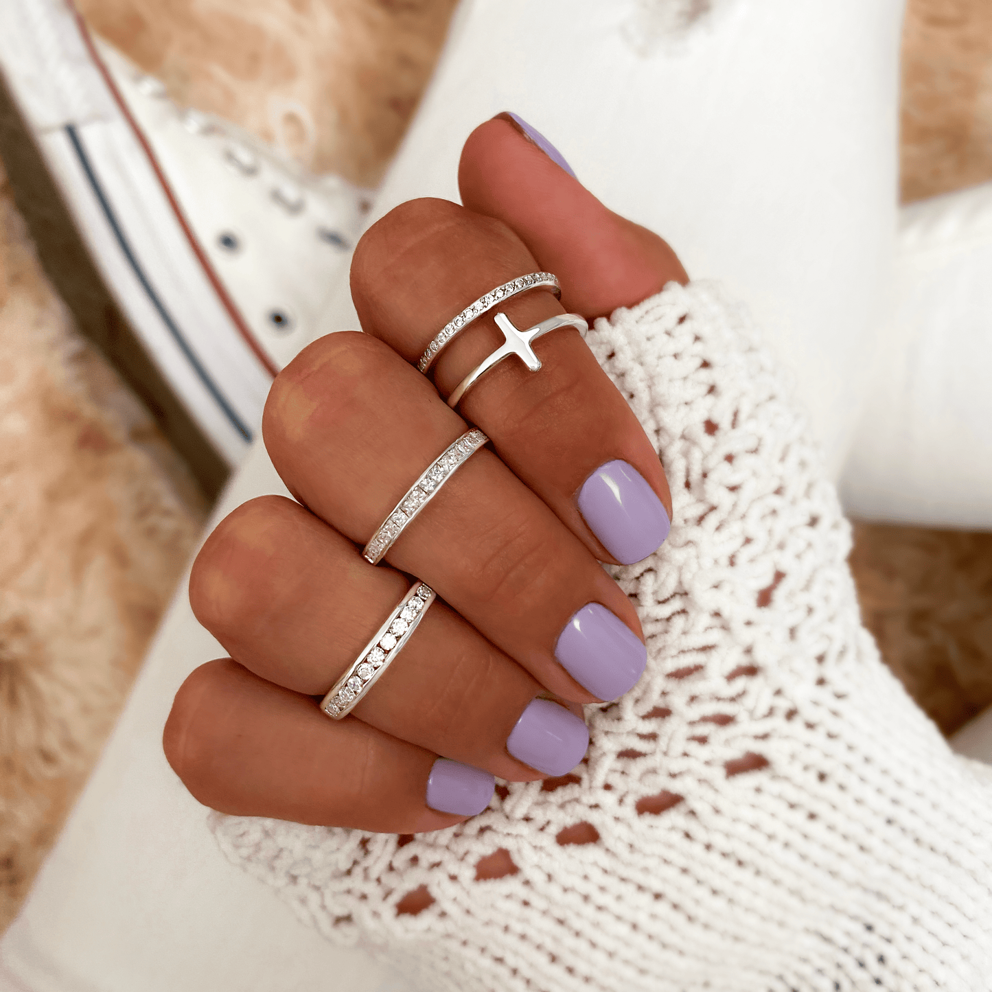 Silberringe mit Kreuzdesign, lila Nagellack, gestrickter Handschuh, Damenmode Accessoires.