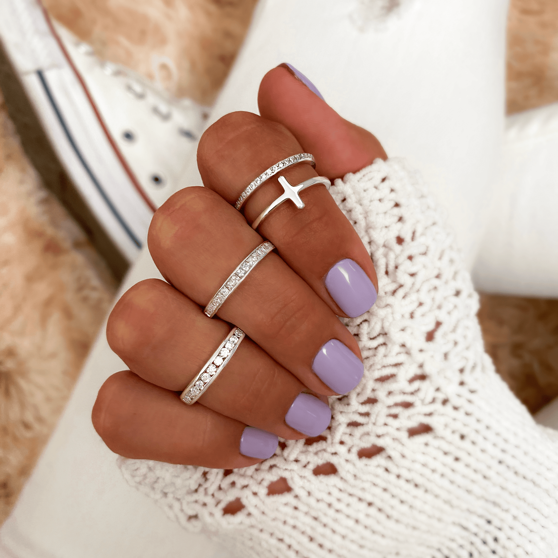 Silberringe mit Kreuzdesign, lila Nagellack, gestrickter Handschuh, Damenmode Accessoires.