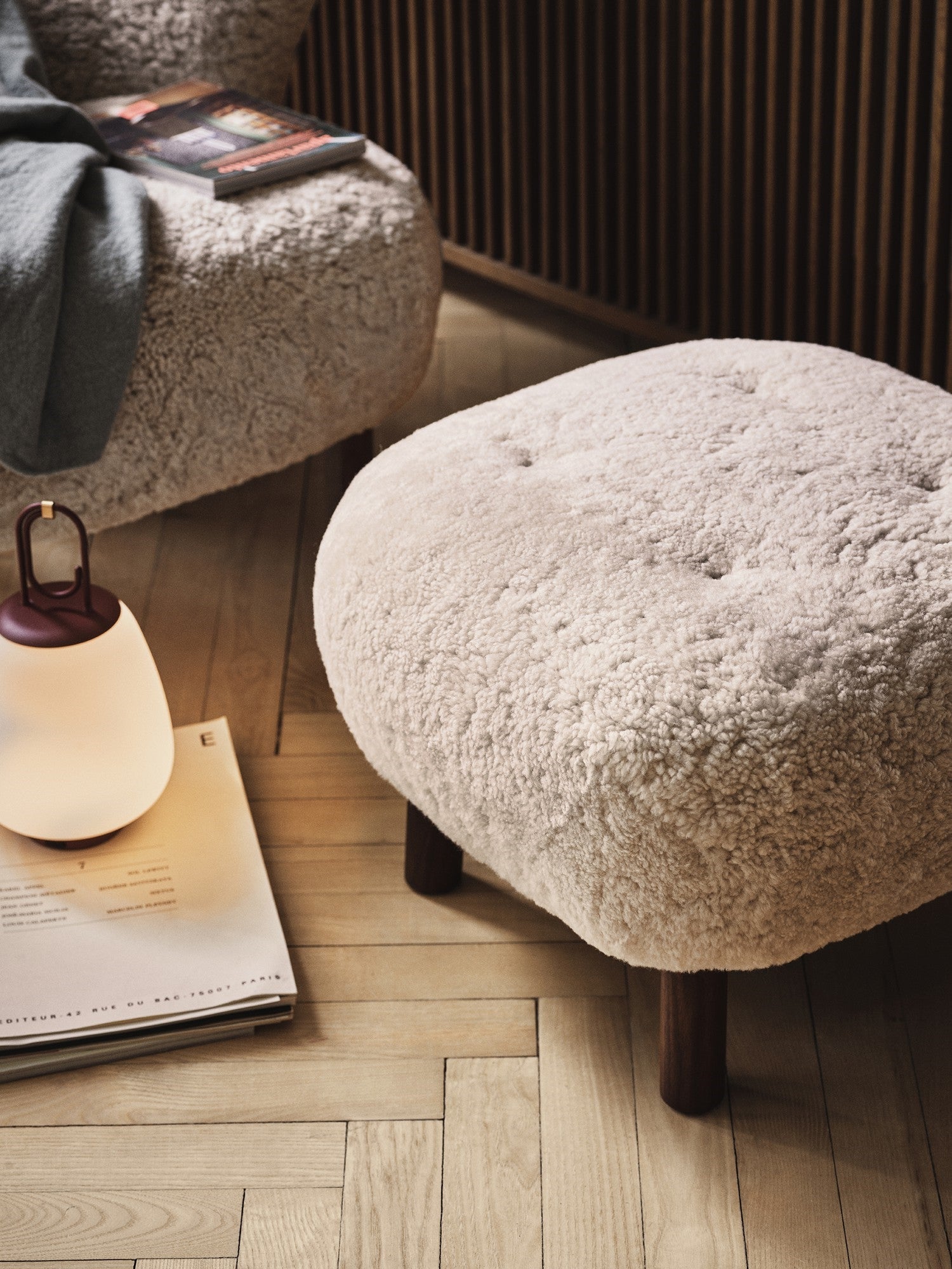 Beiger Schaffell-Hocker auf Holzboden, skandinavisches Design, gemütliche Wohnzimmerdekoration.