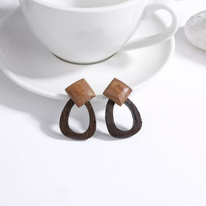 Holzohrringe vor weißer Tasse, geometrisches Design, handgefertigt, modisch, nachhaltig.