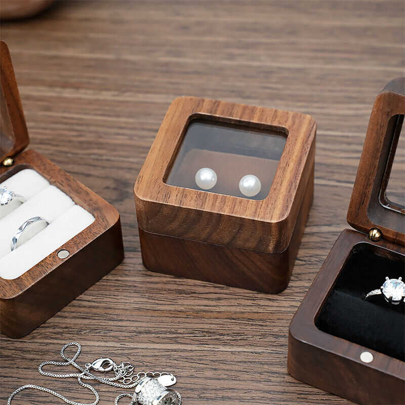 Holzschmuckkästchen mit Glasdeckel, enthält Perlenohrringe, auf Holztisch, elegantes Design.