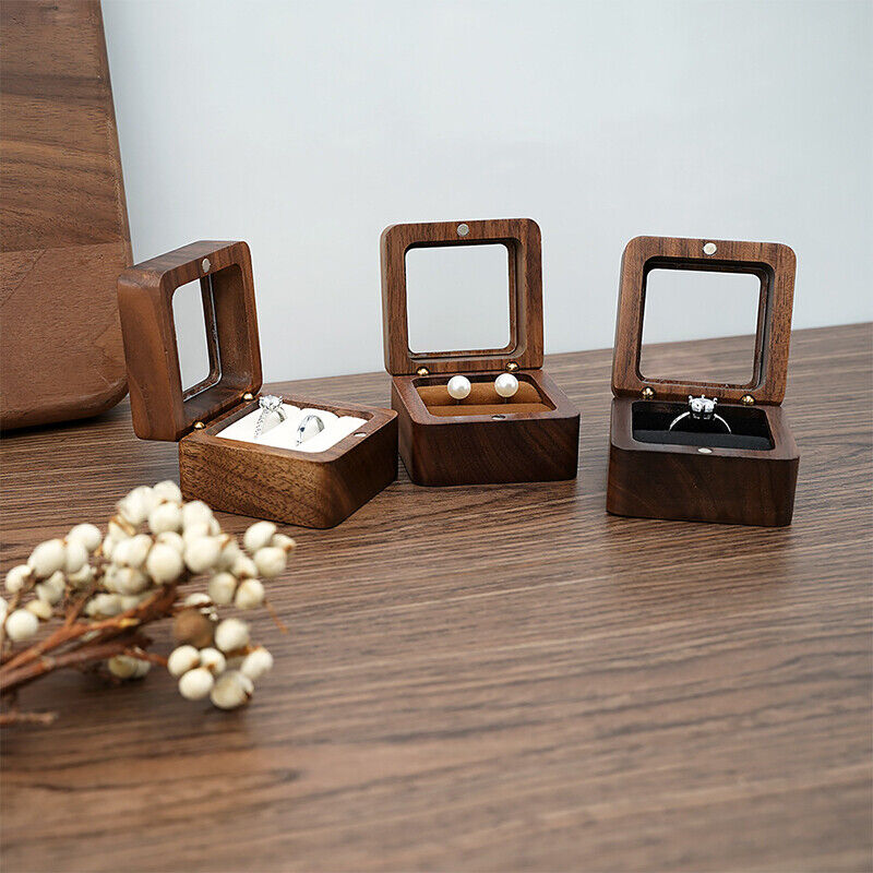 Drei offene Holzschmuckkästchen mit Ringen und Ohrringen auf Holztisch.