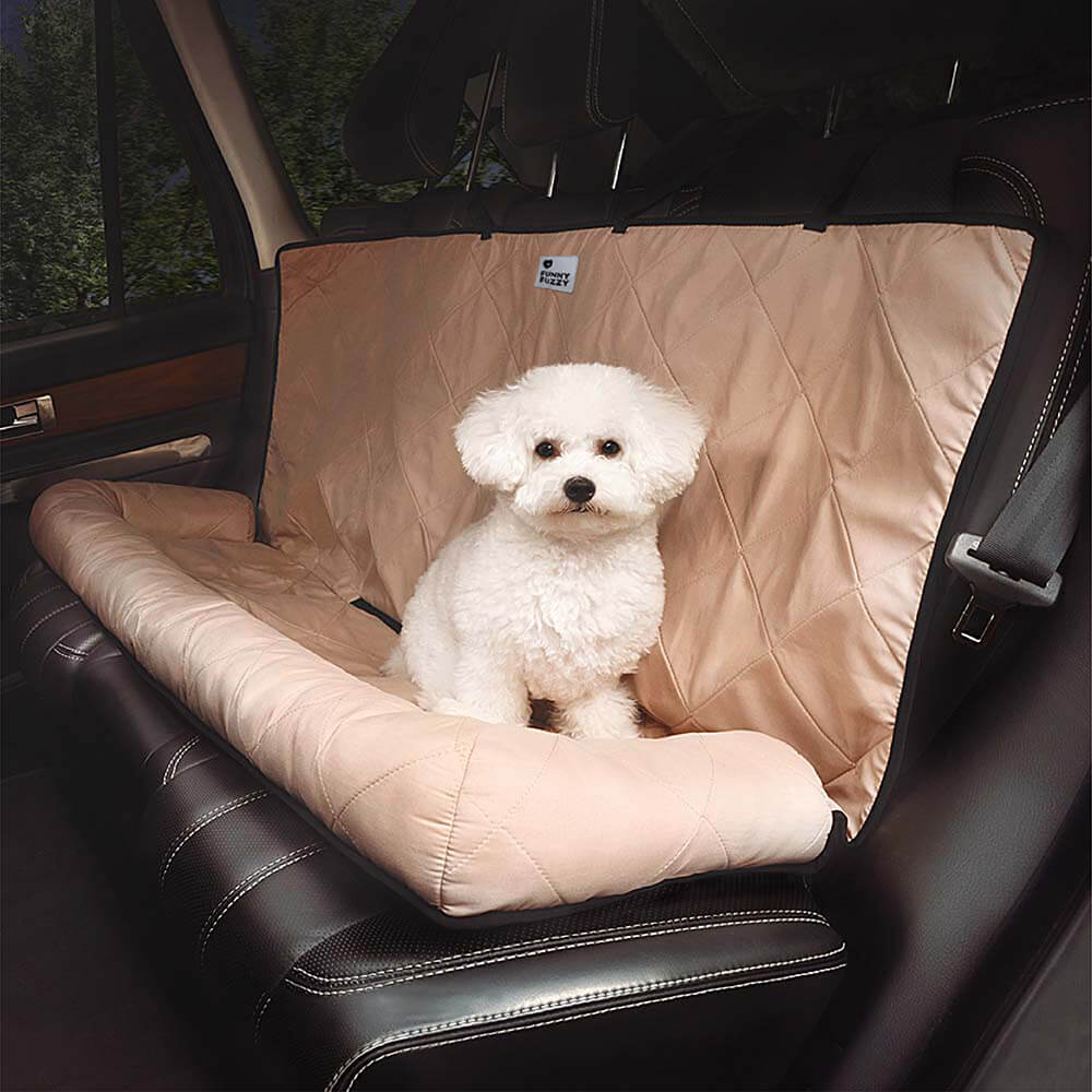 Weißer Hund auf beigem, gestepptem Autositzbezug für Hunde im Auto.
