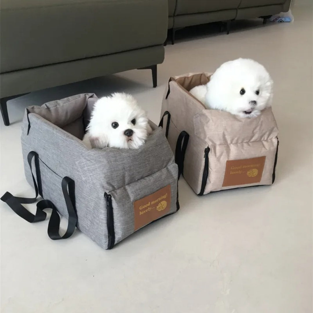 Zwei weiße Hunde in grauen und beigen Hundetragetaschen auf hellem Boden.
