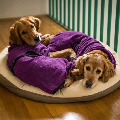 Zwei Hunde in lila Frottee-Bademänteln auf Hundebett, Holzfußboden, gemütlich, Haustierpflege.